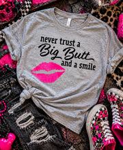 Load image into Gallery viewer, Never trust a big butt and a smile funny graphic tee - Mavictoria Designs Hot Press Express
