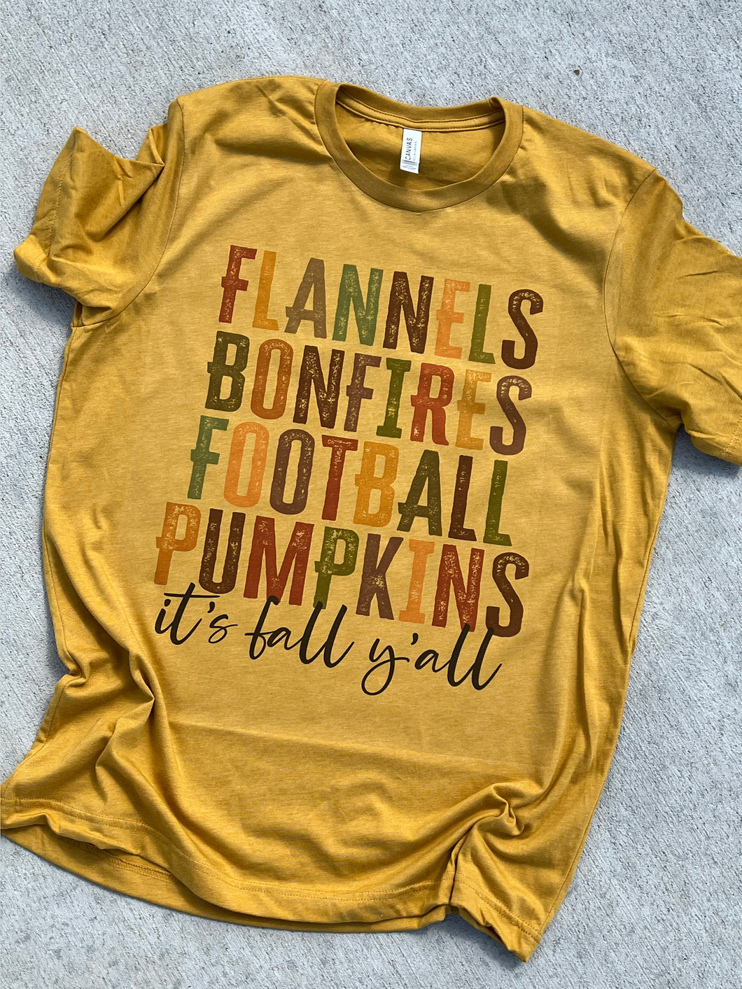 Flannels Bonefires Football Pumpkins it’s fall y’all graphic shirt on heather mustard yellow - Mavictoria Designs Hot Press Express